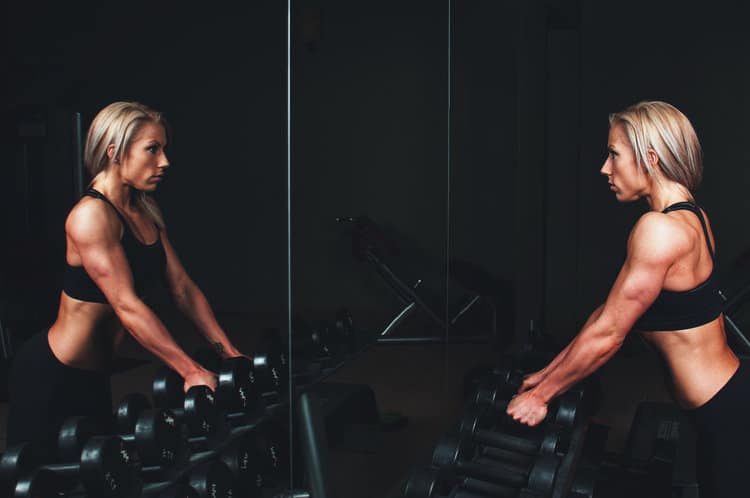 Fit woman looking at her reflection in a gym