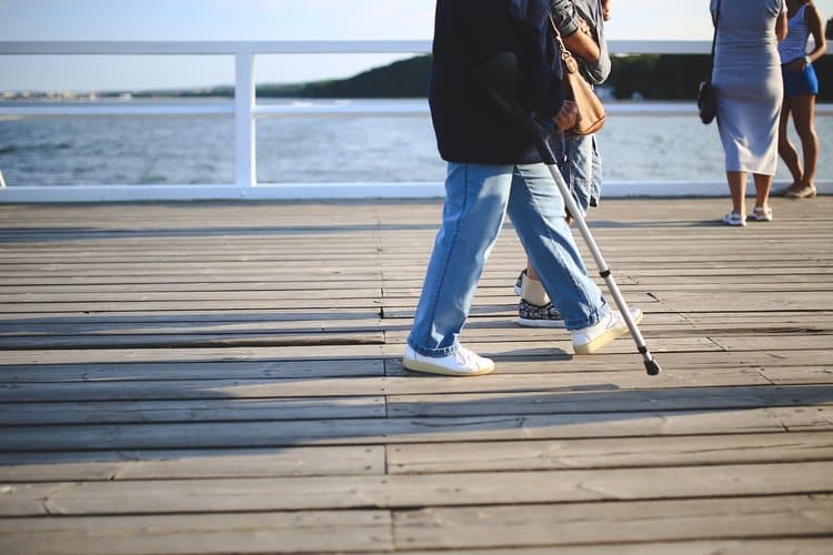 Man on crutch walking along a beach platform