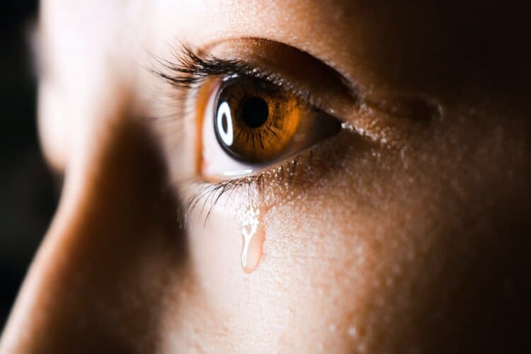 Closeup shot of a tear coming down from a person's eye.