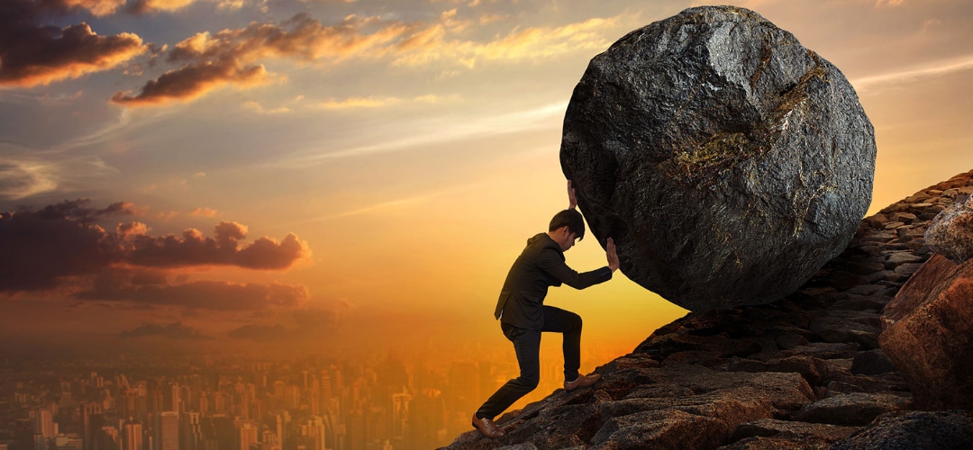 man demonstrating hard work by rolling a boulder up a mountain