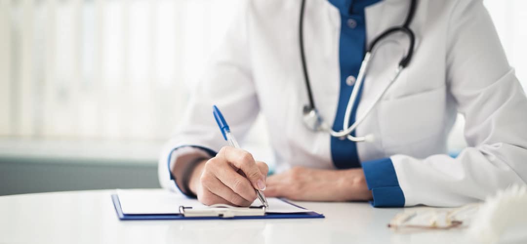 medical professional in a private medical practice filing out a form on a clipboard